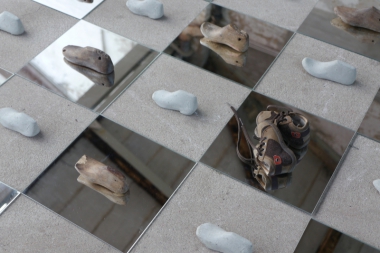 detail from an art installation with old casts for shoes for children on mirror tiles